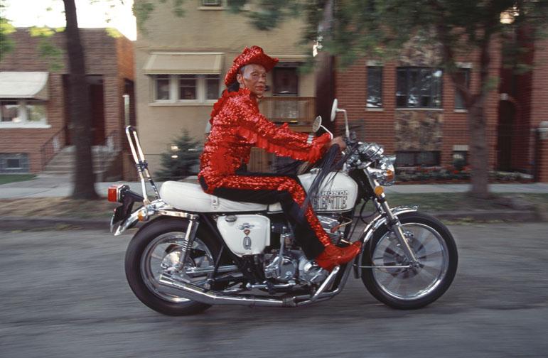 Near 35th Street and Oakley Avenue, Queenie, a lifelong motorcycle enthusiast, tools about in celebration of her 68th birthday. Her Honda is emblazoned with her name scrolled on the gas tank, and she proclaims that she has been riding motorcycles since she was 12 years old.
