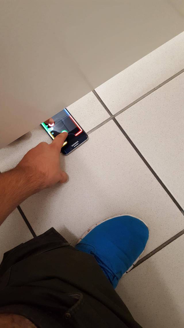 Two friends playing a mobile game in the bathroom in neighboring stalls